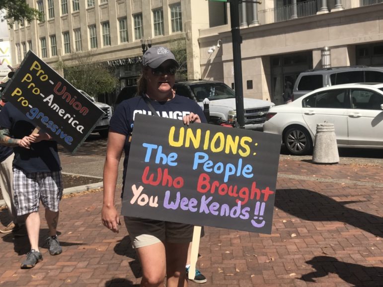 Two people holding signs promoting unions.