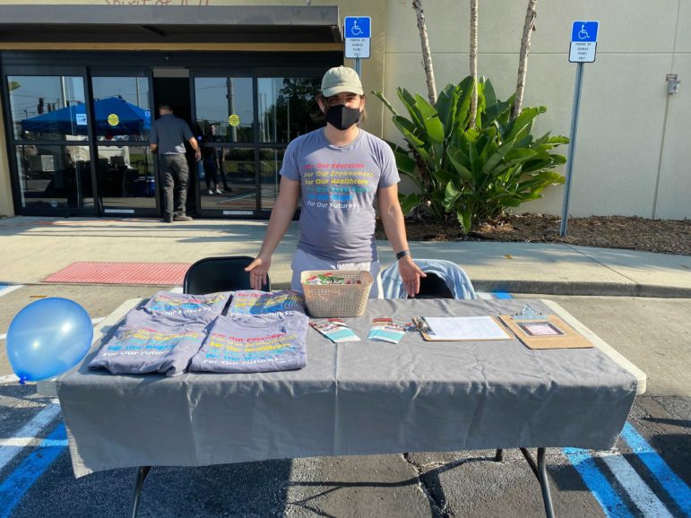 A person stands behind a table promoting Fund Our Future.